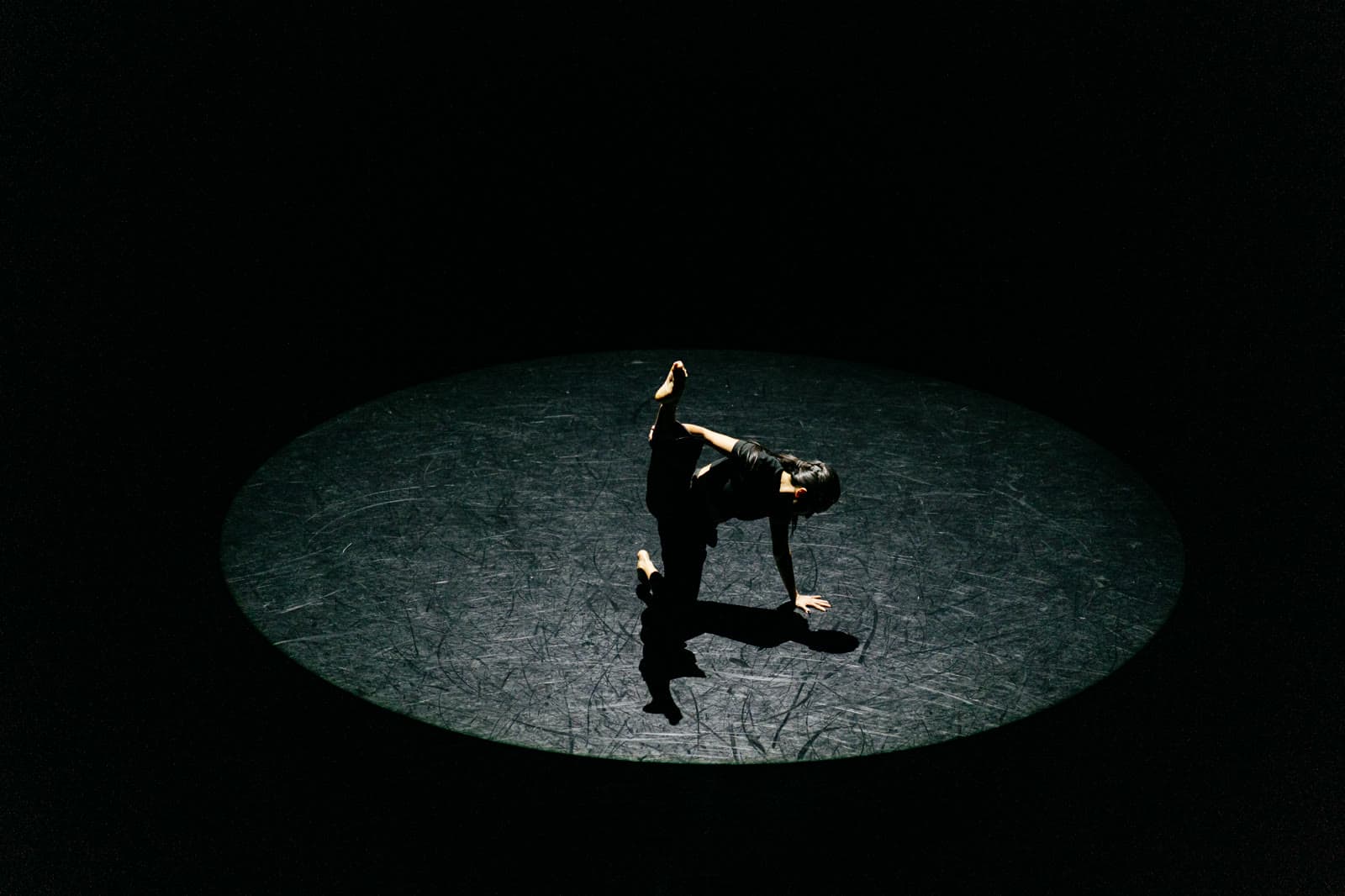 Amberly low to the floor under a single spotlight